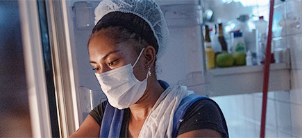 A woman wearing a mask and hair net.