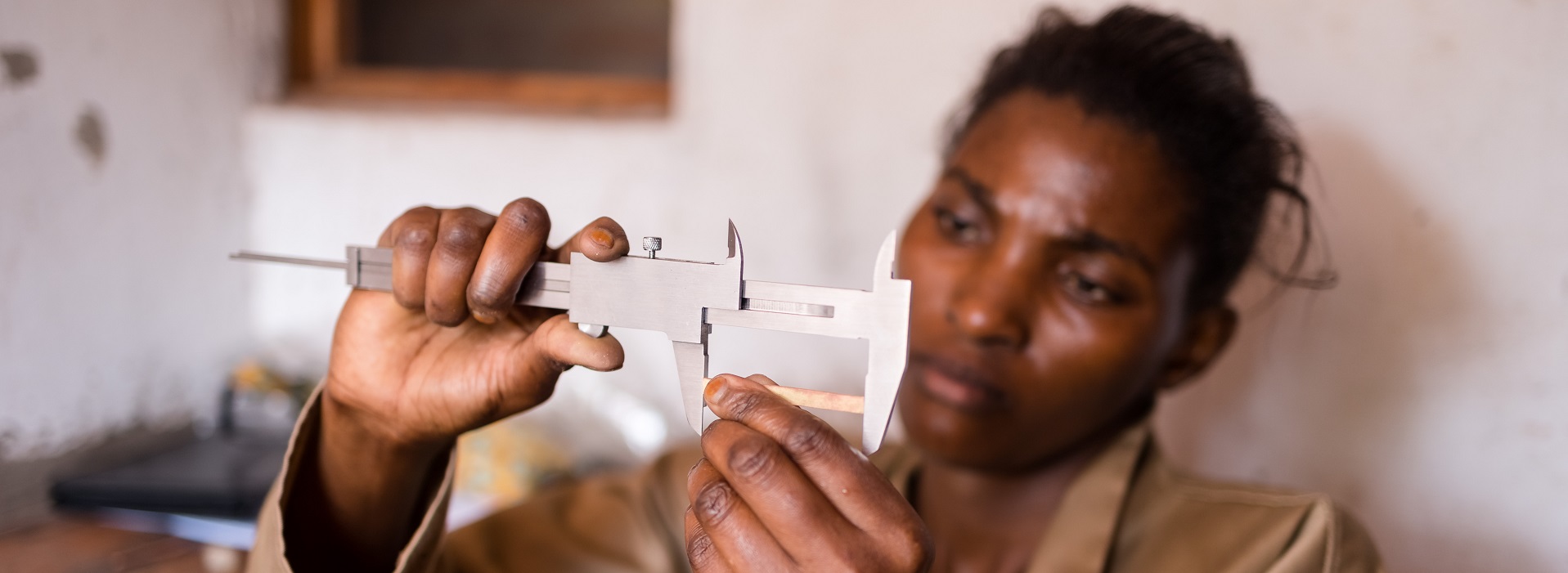 A person holding a small metal caliper.