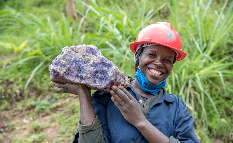 A person wearing a hard hat and holding a large rock.