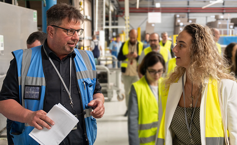 A man and a woman talk during a warehouse tour.