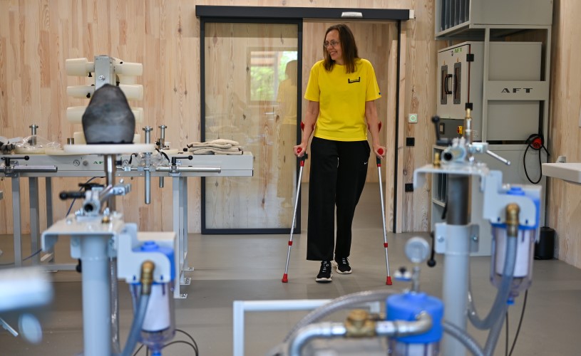 A woman with walking aids looks around the workshop.