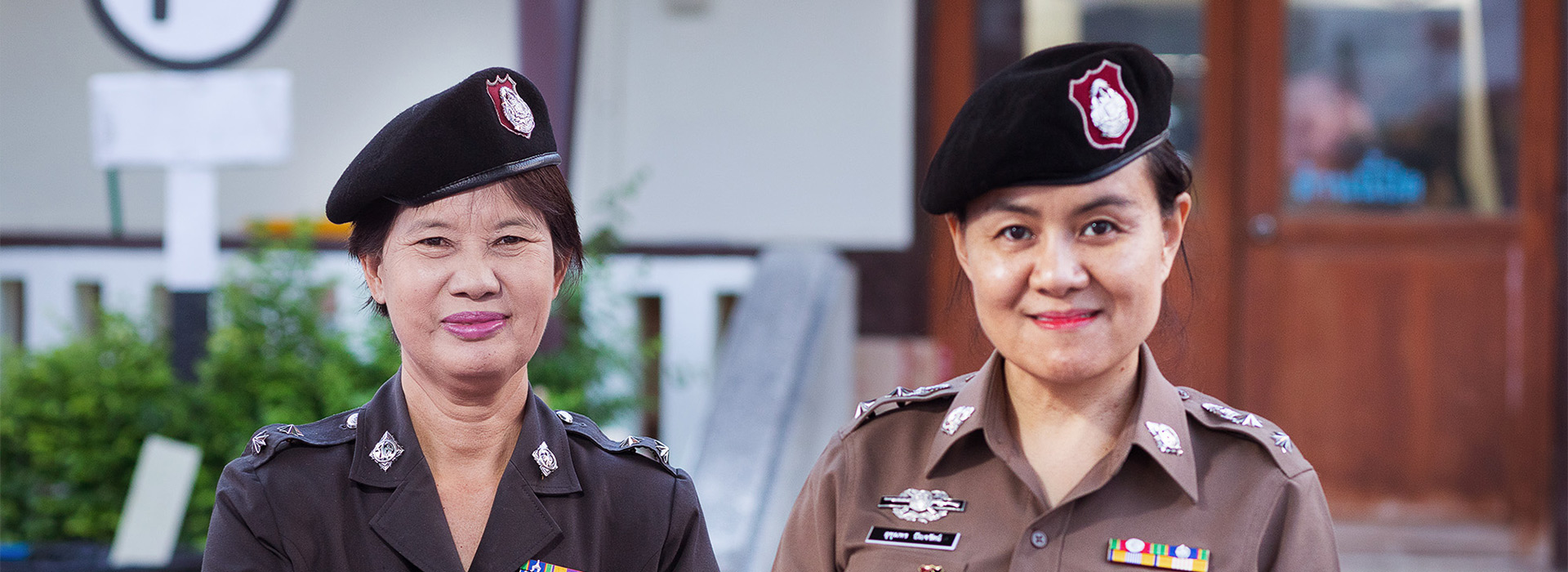 Two smiling policewomen with many badges.